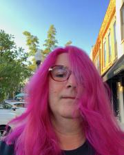 photo of C Marshall outside with Pink hair and pink glasses